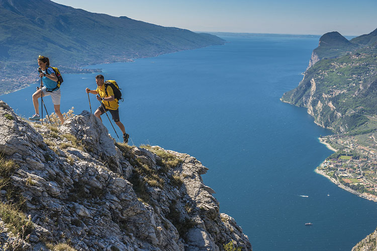 Hikers on a mountain trail overlooking Lake Garda